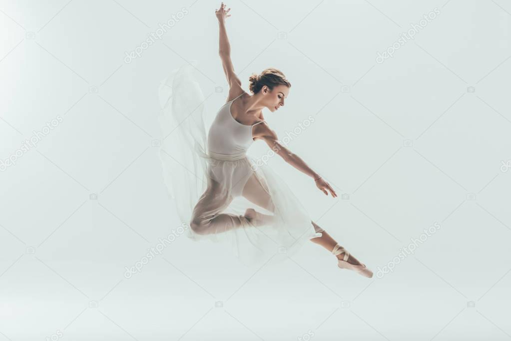 beautiful ballet dancer in white dress jumping in studio, isolated on white