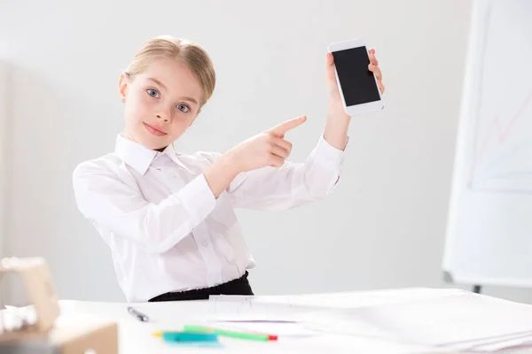 Mignonne petite fille pointant vers smartphone — Photo de stock