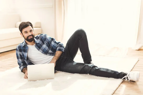 Mann liegt auf Teppich und benutzt Laptop — Stockfoto