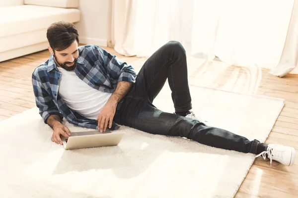 Homem deitado no tapete e usando laptop — Fotografia de Stock