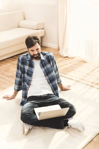 Homme assis sur le tapis et regardant moniteur — Photo de stock