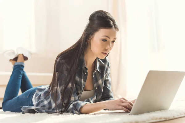 Frau liegt auf Teppich und benutzt Laptop — Stockfoto