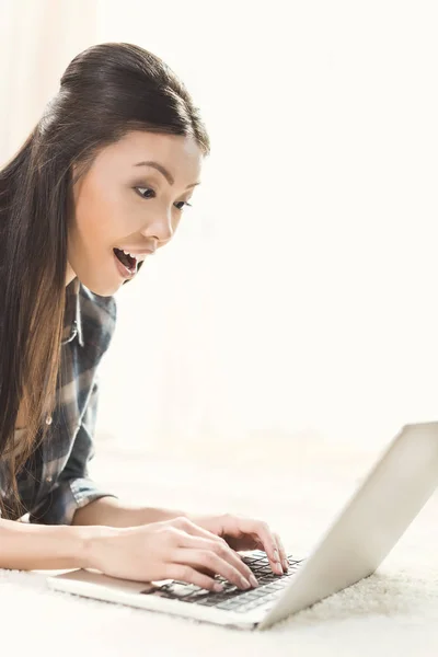 Femme couchée sur le tapis et utilisant un ordinateur portable — Photo de stock