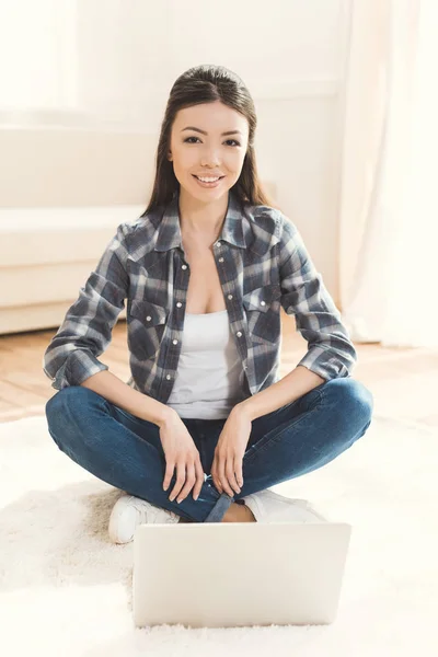 Frau sitzt auf Teppich und blickt in Kamera — Stockfoto