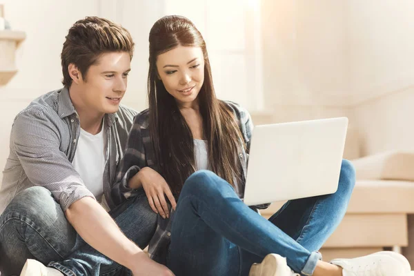 Couple sitting on floor and looking at laptop — Stock Photo
