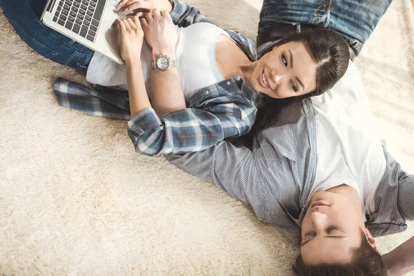 Женщина лежит на парне и использует ноутбук — стоковое фото