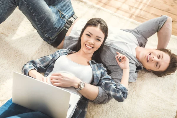 Femme couché sur petit ami et en utilisant un ordinateur portable — Photo de stock