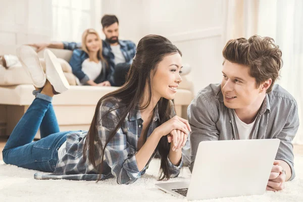 Coppia posa su tappeto e utilizzando il computer portatile — Foto stock