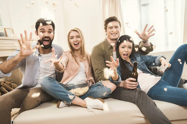 People on couch throwing popcorn upside — Stock Photo