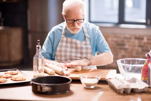 Homme âgé pétrissant la pâte — Photo de stock