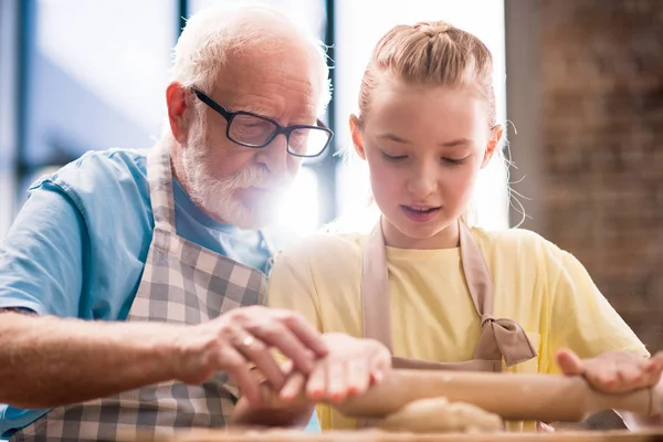 Grandfather and granddaughter making dough — Stock Photo