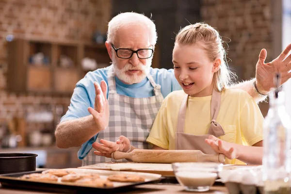 Abuelo y nieta amasando masa - foto de stock