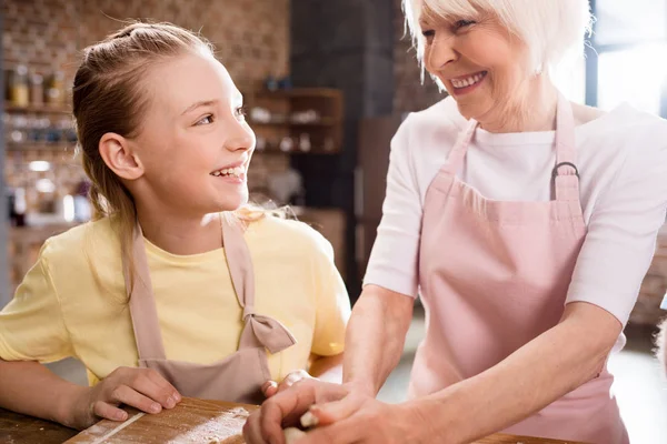 Grandfather and granddaughter kneading dough — Stock Photo