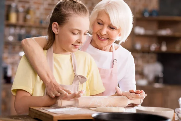 Grandmother and grandchild kneading dough — Stock Photo