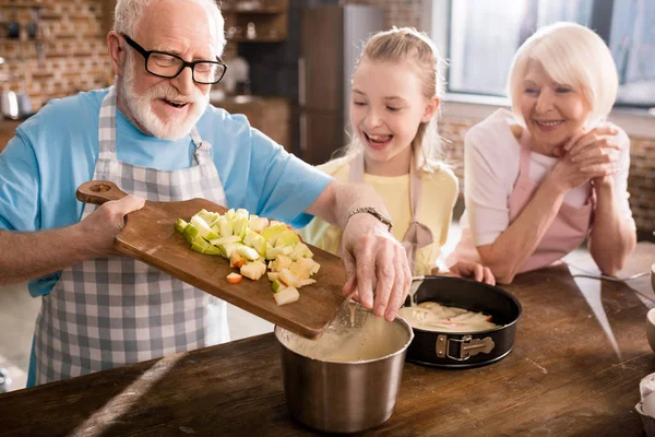 Abuelos y niña cocinar juntos - foto de stock