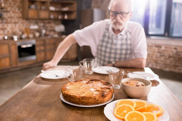 Hombre mayor sentado en la mesa - foto de stock