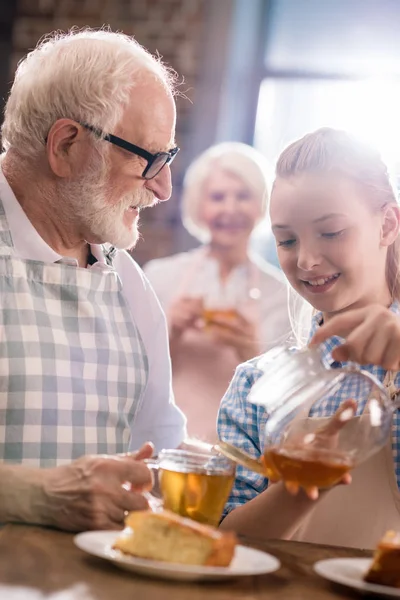 Chica verter té en taza - foto de stock