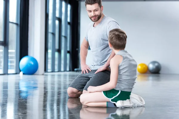 Niño con el hombre joven en el gimnasio - foto de stock