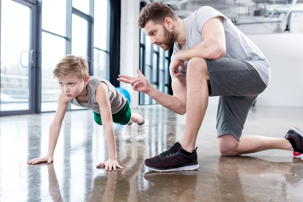 Junge macht Liegestütze mit Trainer — Stockfoto