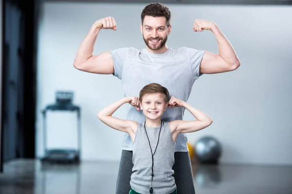 Niño con joven mostrando los músculos - foto de stock