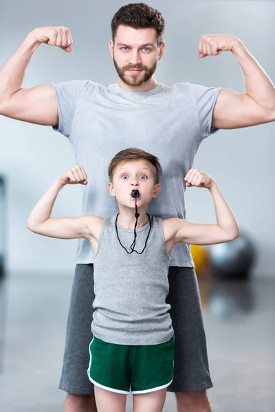 Хлопчик з молодим чоловіком показує м'язи — стокове фото