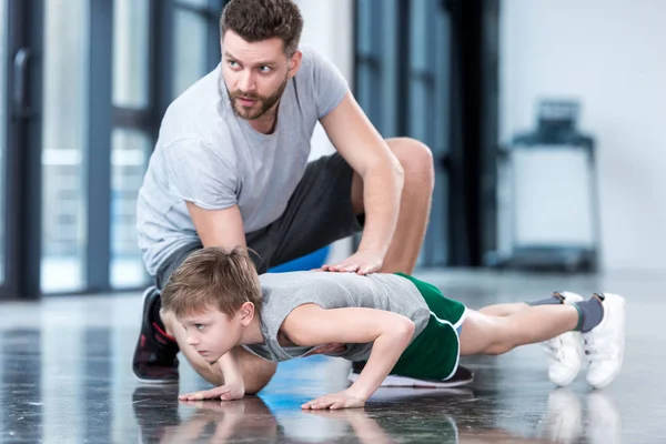 Junge macht Liegestütze mit Trainer — Stockfoto