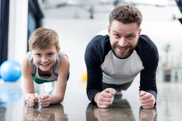 Hombre y niño haciendo ejercicio de tablón - foto de stock