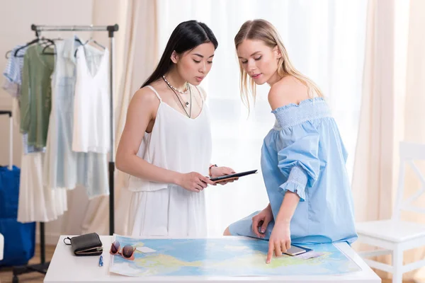 Women travelers looking at world map — Stock Photo
