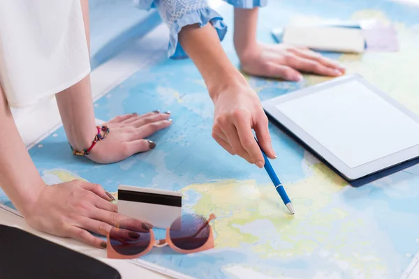 Mujeres viajeros apuntando al mapa del mundo - foto de stock