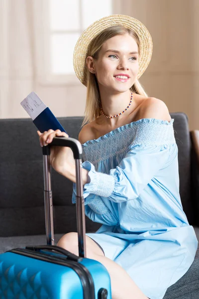 Женщина путешественник сидя с чемоданом и паспортом — стоковое фото