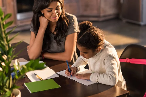 Madre con hija haciendo la tarea - foto de stock