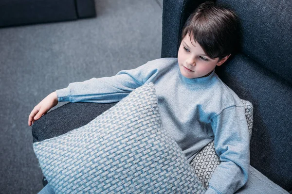 Niño en pijama en sofá - foto de stock