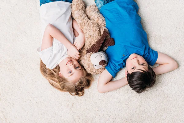 Little boy and girl lying on carpet — Stock Photo