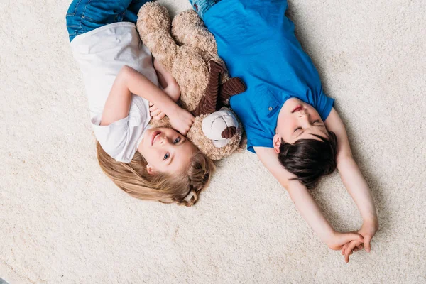 Niño y niña acostados en la alfombra - foto de stock