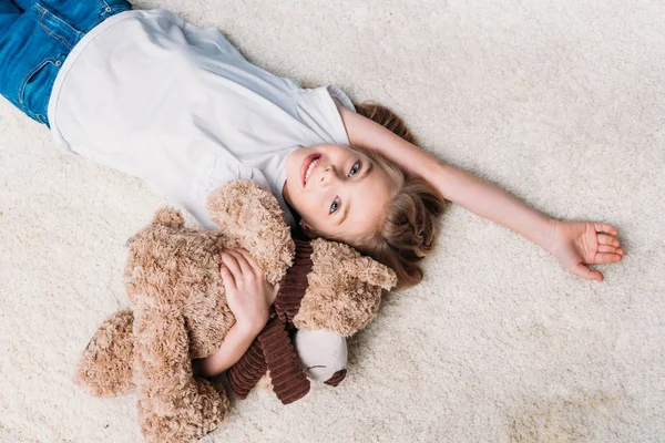 Little girl lying on carpet at home — Stock Photo