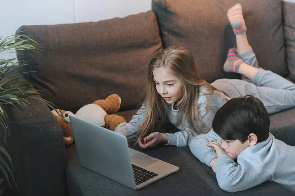 Niño y niña utilizando el ordenador portátil - foto de stock