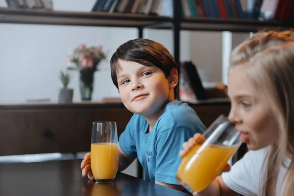 Niño y niña bebiendo jugo de naranja - foto de stock