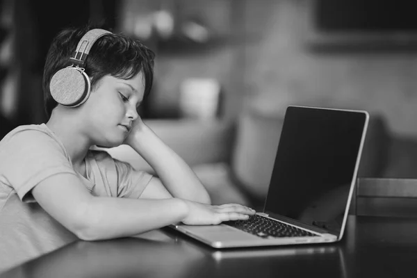 Niño niño en auriculares escribiendo en el ordenador portátil - foto de stock