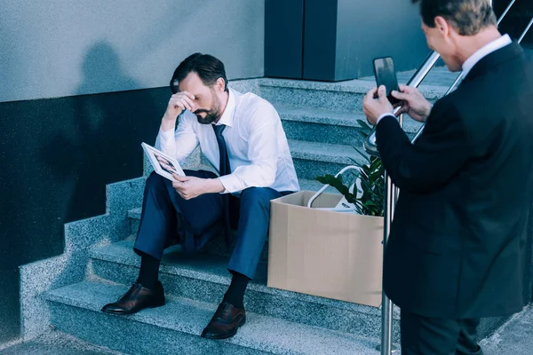 Businessman with smartphone photographing fired colleague — Stock Photo