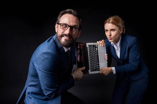 Colegas de negocios luchando por el ordenador portátil - foto de stock