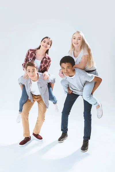 Multicultural adolescentes piggybacking juntos - foto de stock