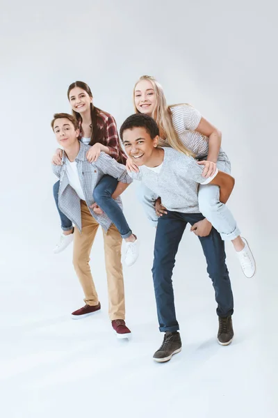 Multicultural adolescentes piggybacking juntos - foto de stock