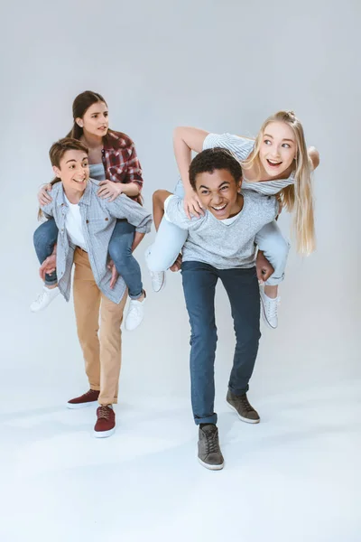 Multicultural adolescentes piggybacking juntos - foto de stock