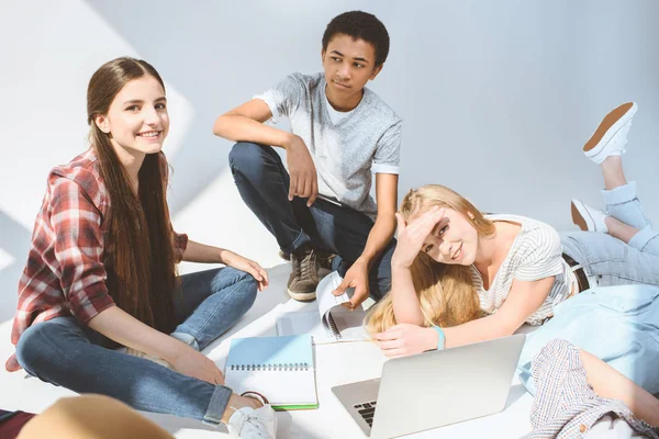 Adolescentes sonrientes multiétnicos con computadora portátil - foto de stock