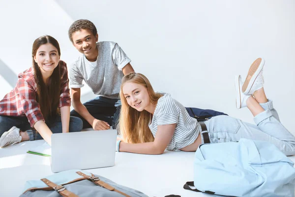 Adolescentes sonrientes multiétnicos con computadora portátil - foto de stock