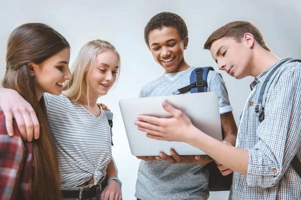 Adolescentes multiétnicos utilizando el ordenador portátil - foto de stock