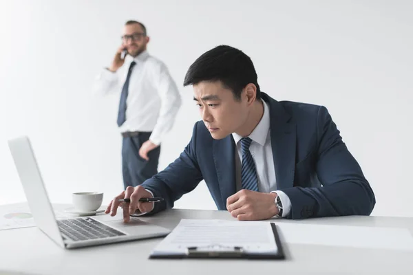 Asian businessman with laptop at workplace — Stock Photo