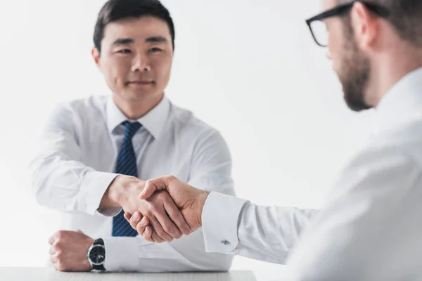 Hombres de negocios multiculturales estrechando la mano en la reunión - foto de stock