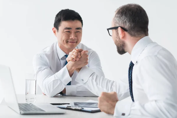 Мультикультурные бизнесмены пожимают друг другу руки на встрече — стоковое фото