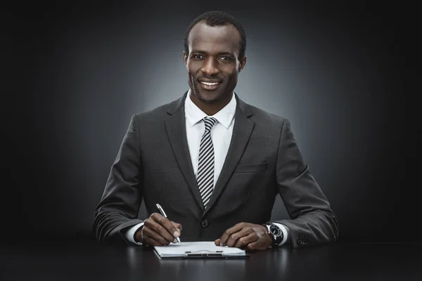 Hombre de negocios afroamericano haciendo papeleo - foto de stock